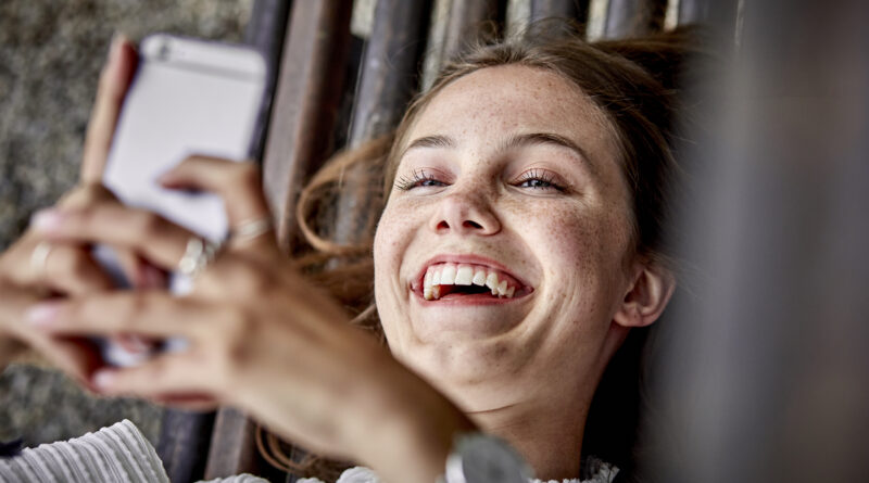 Persona sonriendo viendo celular